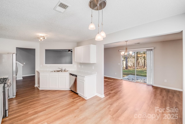 kitchen featuring light wood finished floors, visible vents, light countertops, stainless steel appliances, and a sink