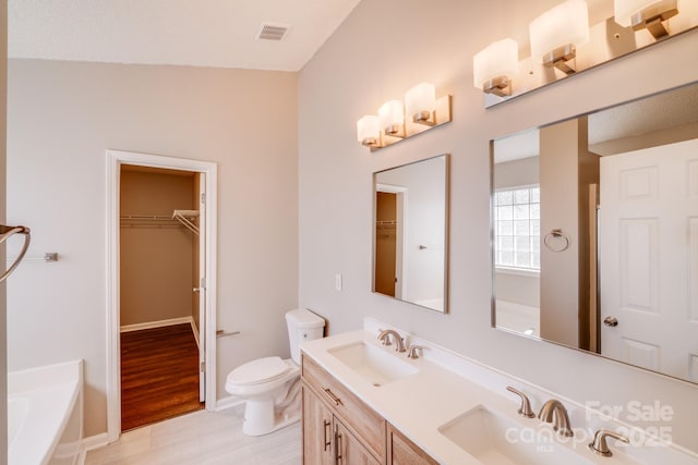 bathroom featuring a bath, visible vents, toilet, and a sink