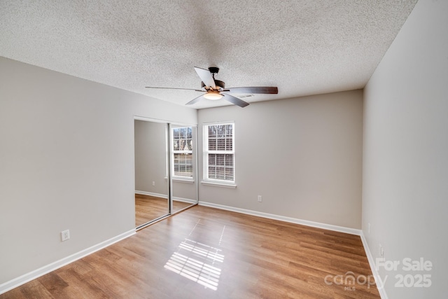 unfurnished bedroom featuring baseboards, a textured ceiling, wood finished floors, and a ceiling fan