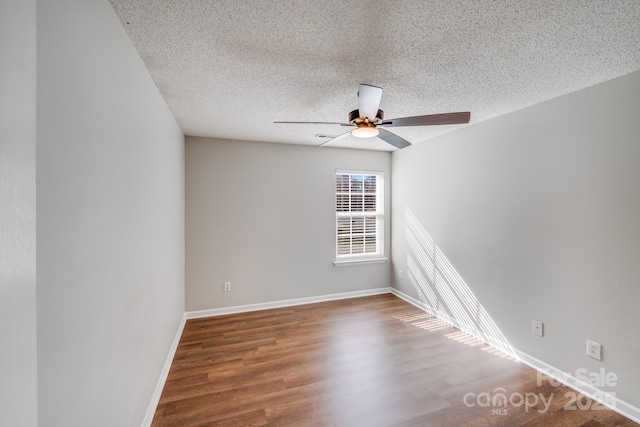 empty room with ceiling fan, baseboards, a textured ceiling, and wood finished floors