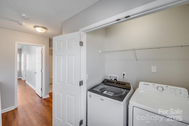 washroom featuring baseboards, laundry area, wood finished floors, independent washer and dryer, and a textured ceiling