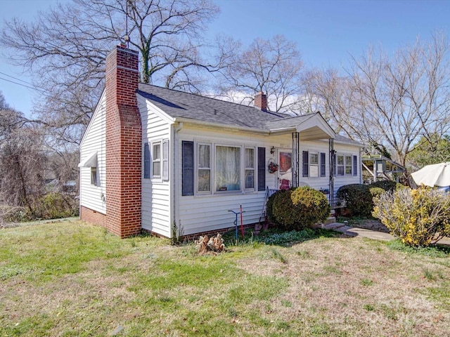 bungalow-style home featuring a shingled roof, a front yard, and a chimney