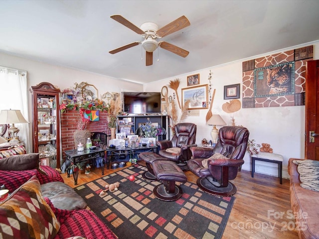 living area with ceiling fan, a fireplace, and wood finished floors