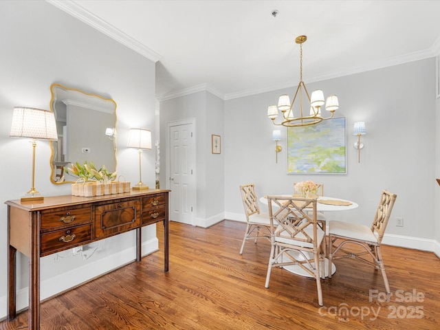 dining area with a chandelier, crown molding, baseboards, and wood finished floors