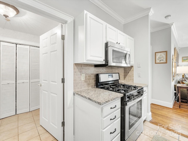 kitchen with ornamental molding, stainless steel appliances, light stone counters, and light tile patterned flooring