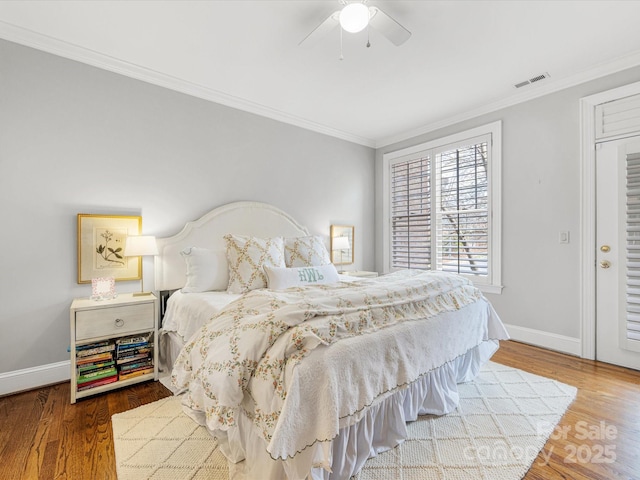 bedroom with crown molding, visible vents, ceiling fan, wood finished floors, and baseboards