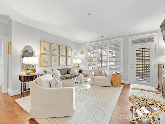 living area with ornamental molding, baseboards, and light wood finished floors