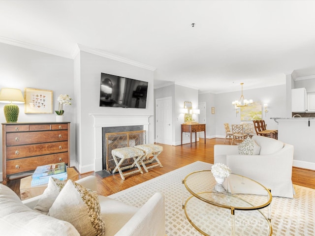 living area with an inviting chandelier, a fireplace with flush hearth, ornamental molding, wood finished floors, and baseboards