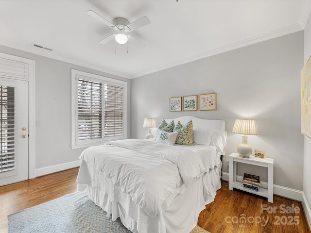 bedroom featuring ornamental molding, wood finished floors, visible vents, and baseboards