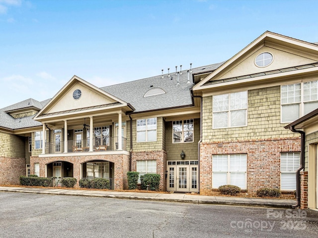 exterior space with a balcony, a standing seam roof, metal roof, and brick siding