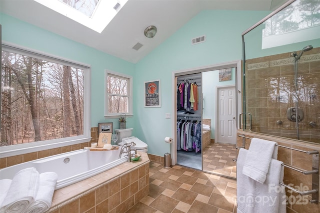 full bath featuring visible vents, a skylight, a shower stall, a bath, and a spacious closet