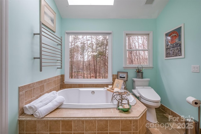 bathroom with visible vents, toilet, radiator heating unit, a skylight, and a bath