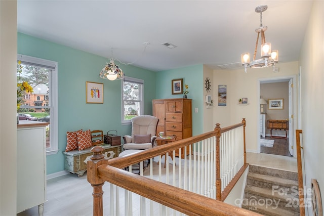 interior space featuring light wood-type flooring, baseboards, an inviting chandelier, and visible vents