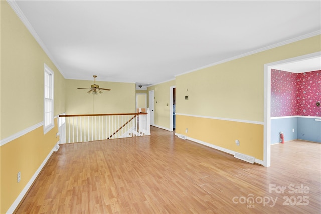 spare room featuring ornamental molding, a ceiling fan, baseboards, and wood finished floors