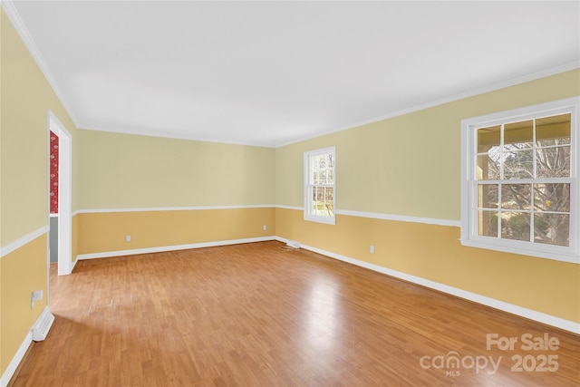 spare room featuring crown molding, baseboards, and wood finished floors