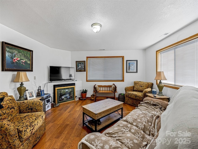 living room featuring a textured ceiling, wood finished floors, and visible vents