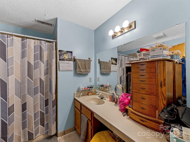 full bathroom with a textured ceiling, curtained shower, visible vents, and vanity