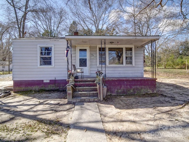 bungalow-style house featuring covered porch and a chimney