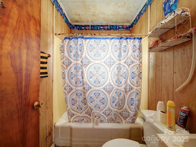 full bath featuring toilet, wooden walls, and shower / bath combination with curtain