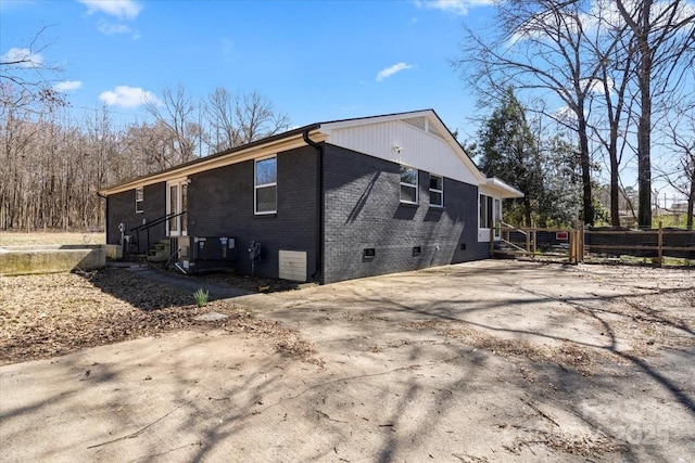 view of home's exterior featuring brick siding, crawl space, and fence