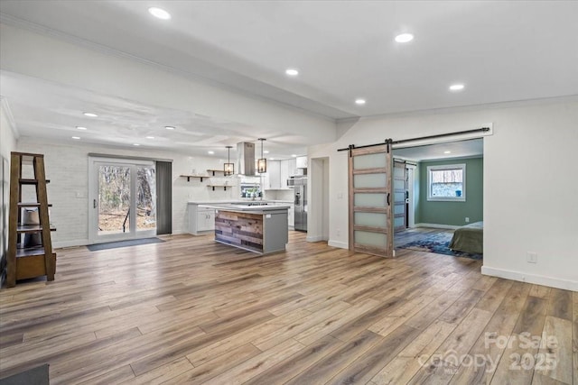 kitchen with light wood finished floors, a barn door, white cabinets, open floor plan, and open shelves