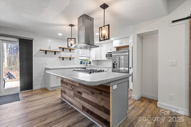 kitchen featuring light countertops, a barn door, appliances with stainless steel finishes, island range hood, and wood finished floors