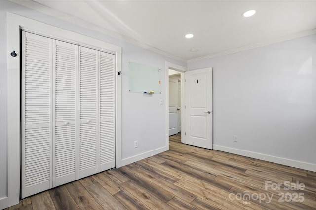 unfurnished bedroom featuring crown molding, recessed lighting, a closet, wood finished floors, and baseboards