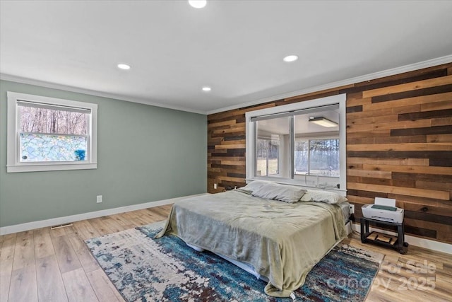 bedroom with ornamental molding, wood finished floors, and wooden walls