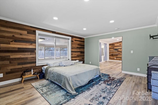 bedroom featuring ornamental molding, wooden walls, baseboards, and wood finished floors