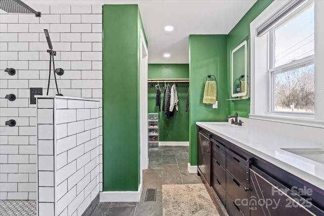 bathroom with a walk in shower, double vanity, a sink, and visible vents