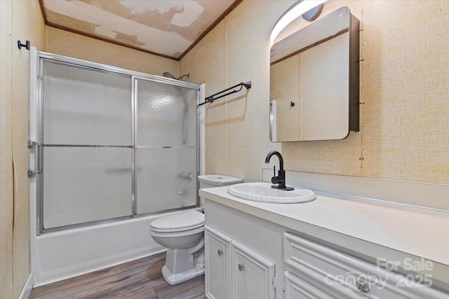 full bath featuring enclosed tub / shower combo, toilet, wood finished floors, vanity, and crown molding