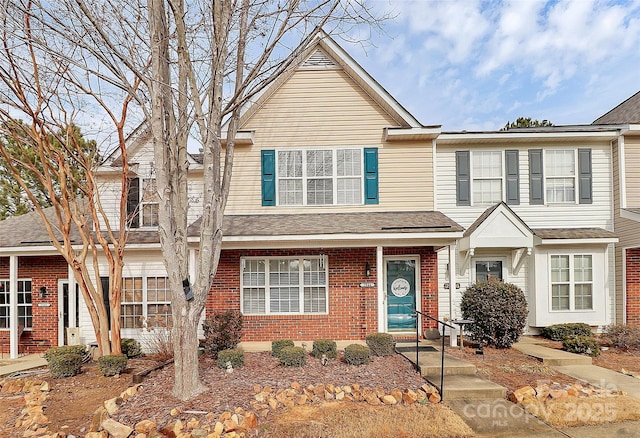 view of front of property with a shingled roof and brick siding