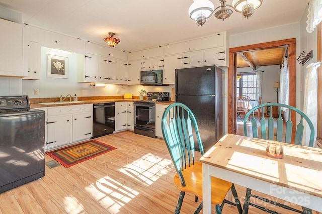 kitchen with a chandelier, a sink, white cabinets, black appliances, and light wood finished floors