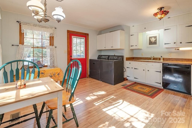 kitchen featuring light wood-style flooring, a sink, white cabinets, dishwasher, and washer and clothes dryer