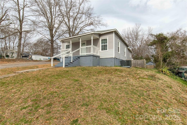 bungalow featuring covered porch, a front lawn, central AC unit, and fence