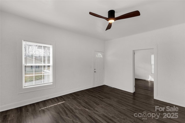 spare room with ceiling fan, baseboards, and dark wood-type flooring