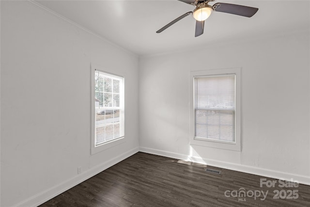 spare room with dark wood-style floors, visible vents, baseboards, and crown molding