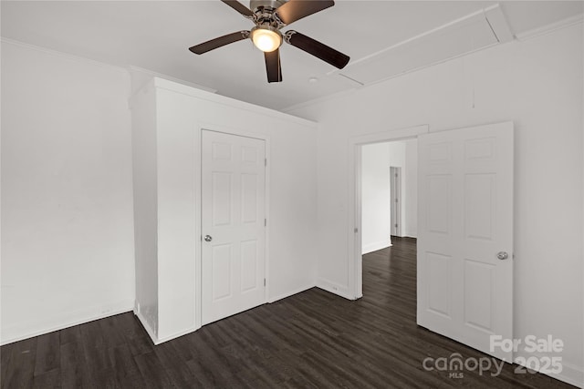 unfurnished bedroom with attic access, baseboards, ceiling fan, ornamental molding, and dark wood-type flooring