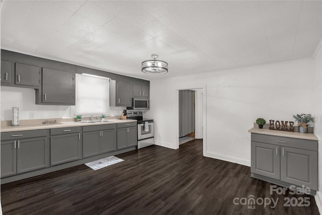 kitchen with stainless steel appliances, gray cabinets, light countertops, and dark wood-style floors