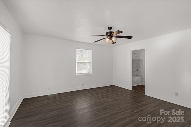 spare room featuring a ceiling fan, visible vents, baseboards, and dark wood-type flooring