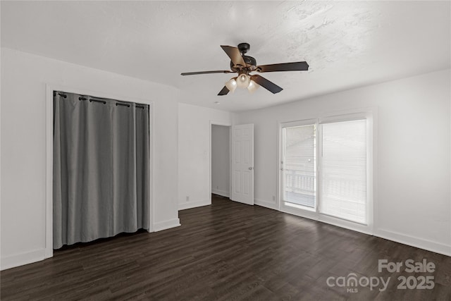 interior space with a ceiling fan, baseboards, and dark wood-style flooring