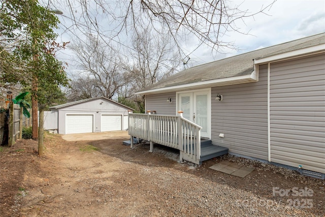 entrance to property with a deck, french doors, a detached garage, and fence