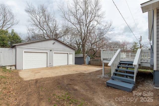 detached garage featuring a storage shed and fence