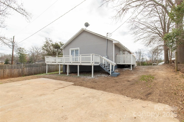 rear view of property featuring fence and a deck