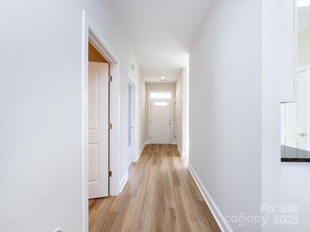 hall featuring light wood-type flooring and baseboards