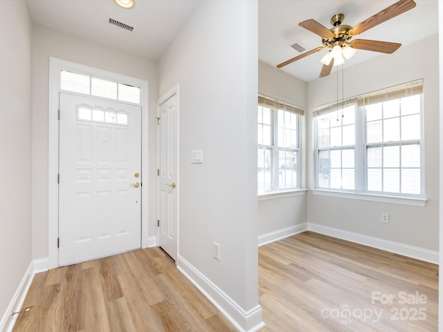 foyer entrance with light wood finished floors, baseboards, and visible vents