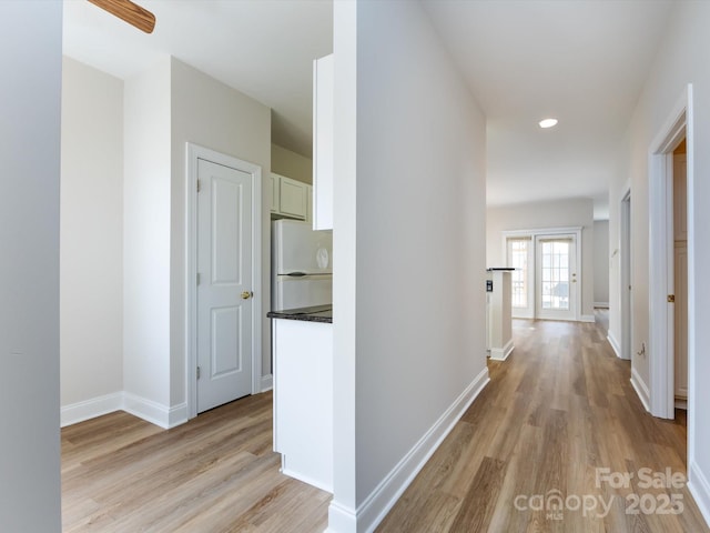 corridor featuring light wood-type flooring and baseboards