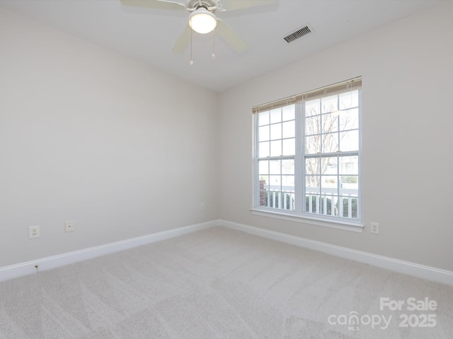 empty room with baseboards, visible vents, a ceiling fan, and light colored carpet