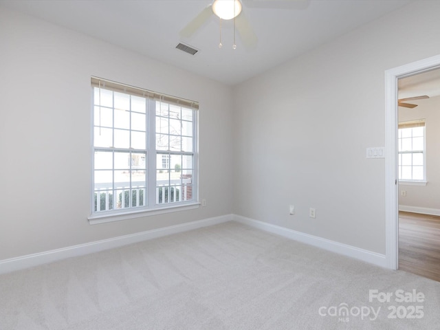 spare room featuring carpet floors, ceiling fan, visible vents, and baseboards