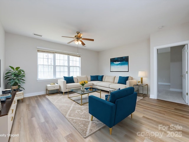 living room with a ceiling fan, light wood-type flooring, visible vents, and baseboards